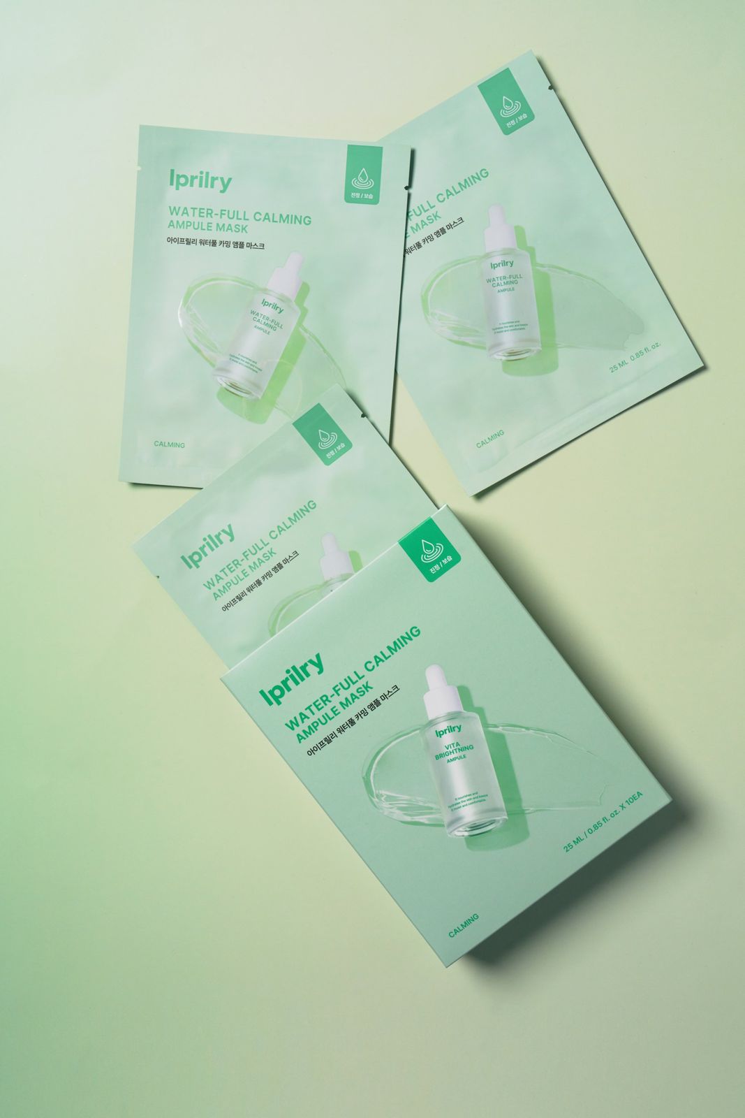 Iprilry · 아이프릴리 카밍마스크 — 워터풀 카밍 앰플 마스크 낱개 파우치 여러 장과 박스를 함께 펼쳐놓은 그룹 컷, 그린 배경