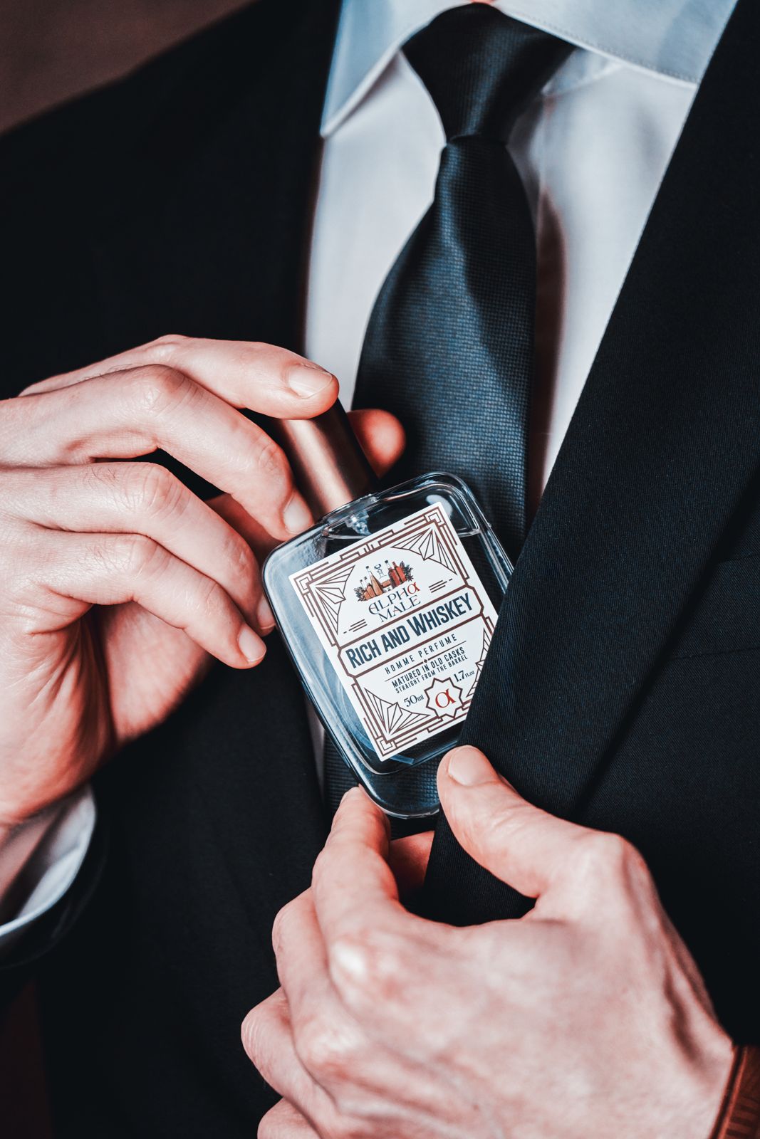 ALPHAMOOD · 모델촬영 — 양손으로 넥타이를 매만지며 그 사이에 Rich and Whiskey 병을 든 클로즈업 컷