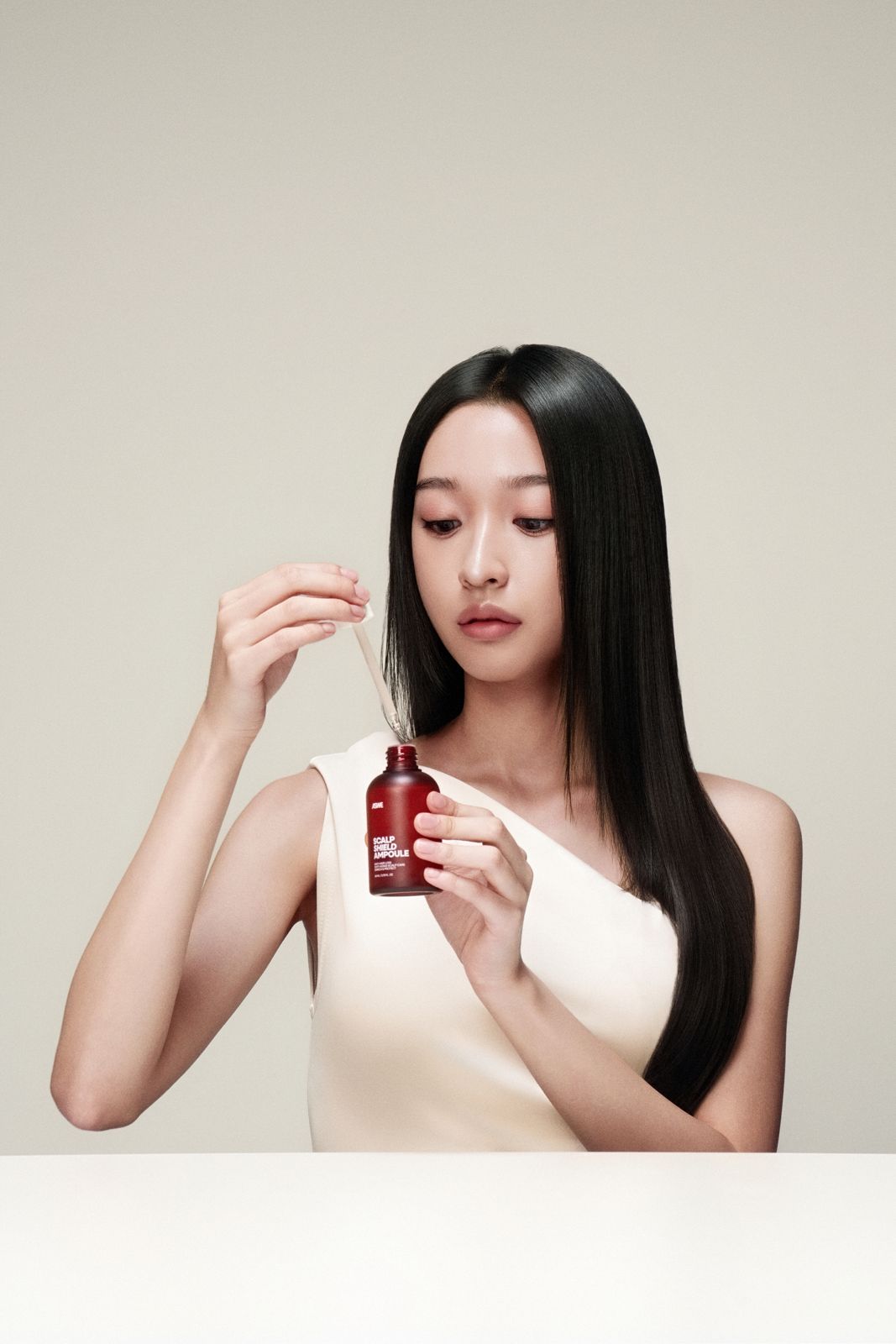 ASWE · 두피앰플 (모델컷) — 병에서 드로퍼로 제형을 떠올리는 모델컷, 베이지 배경