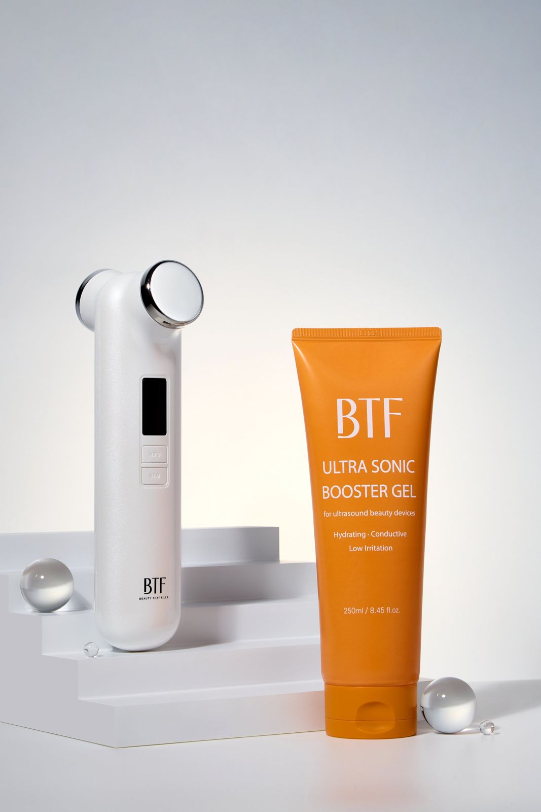 BTF · 부스터젤 — BTF 디바이스와 부스터젤을 계단식 좌대 위에 함께 연출한 컷