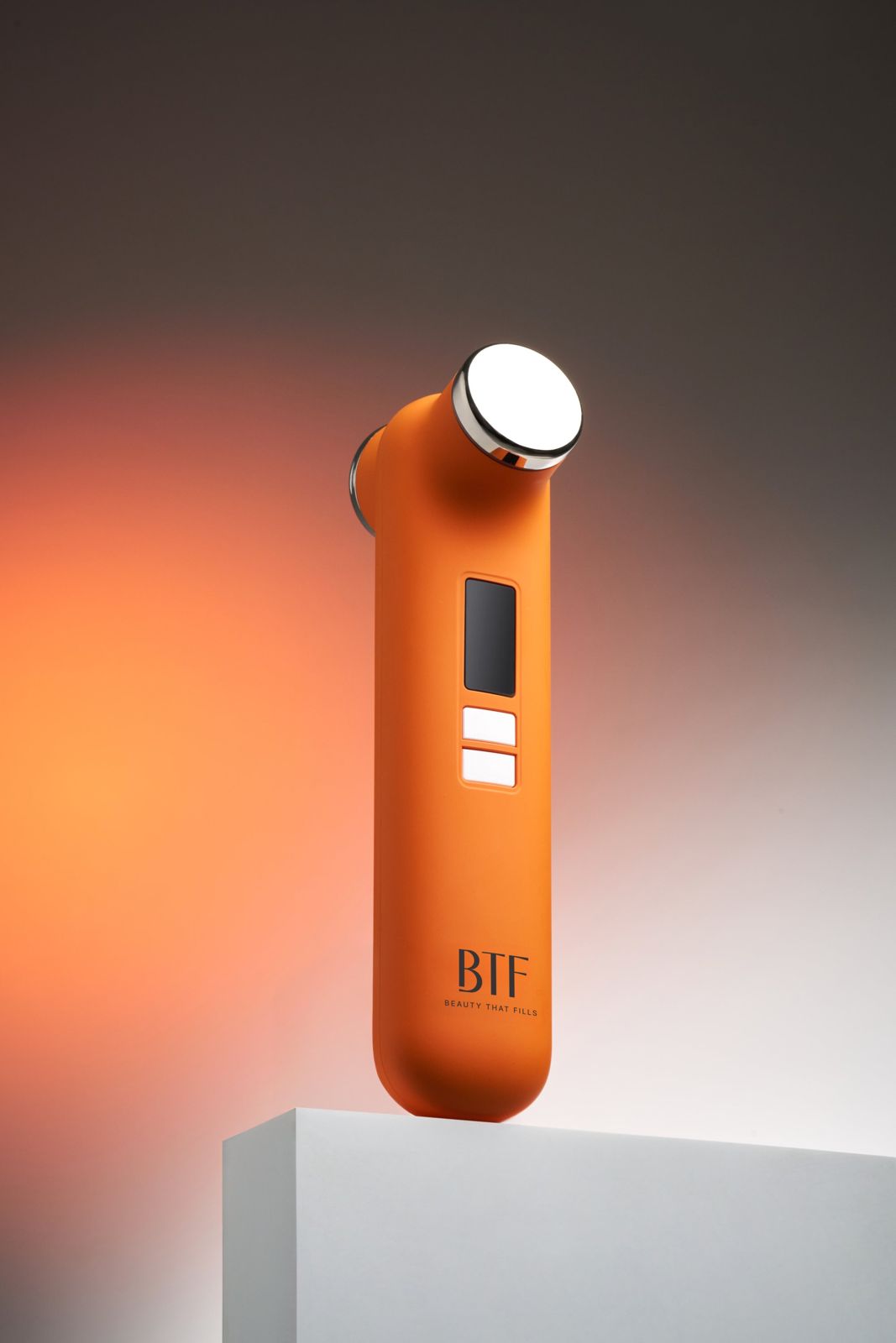 BTF · 듀오 디바이스 — 오렌지 디바이스를 화이트 큐브 위에 올린 컷, 오렌지 그라데이션 배경