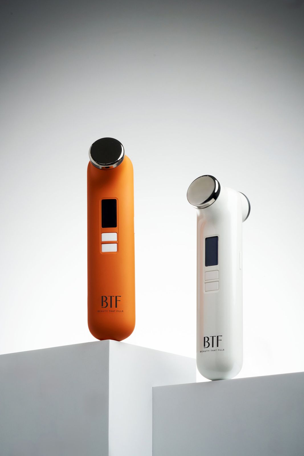 BTF · 듀오 디바이스 — 두 컬러 디바이스를 각각 큐브 좌대 위에 올린 그룹컷, 화이트 배경