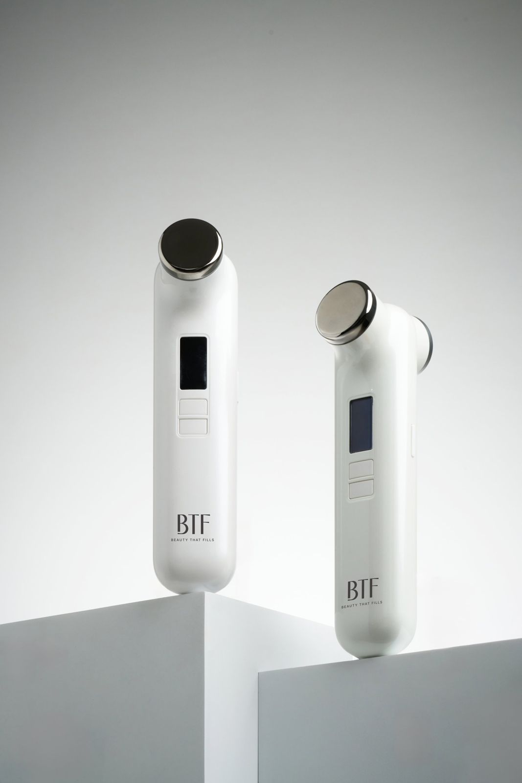 BTF · 듀오 디바이스 — 두 컬러 디바이스를 큐브 좌대 위에 올린 근접 그룹컷, 화이트 배경