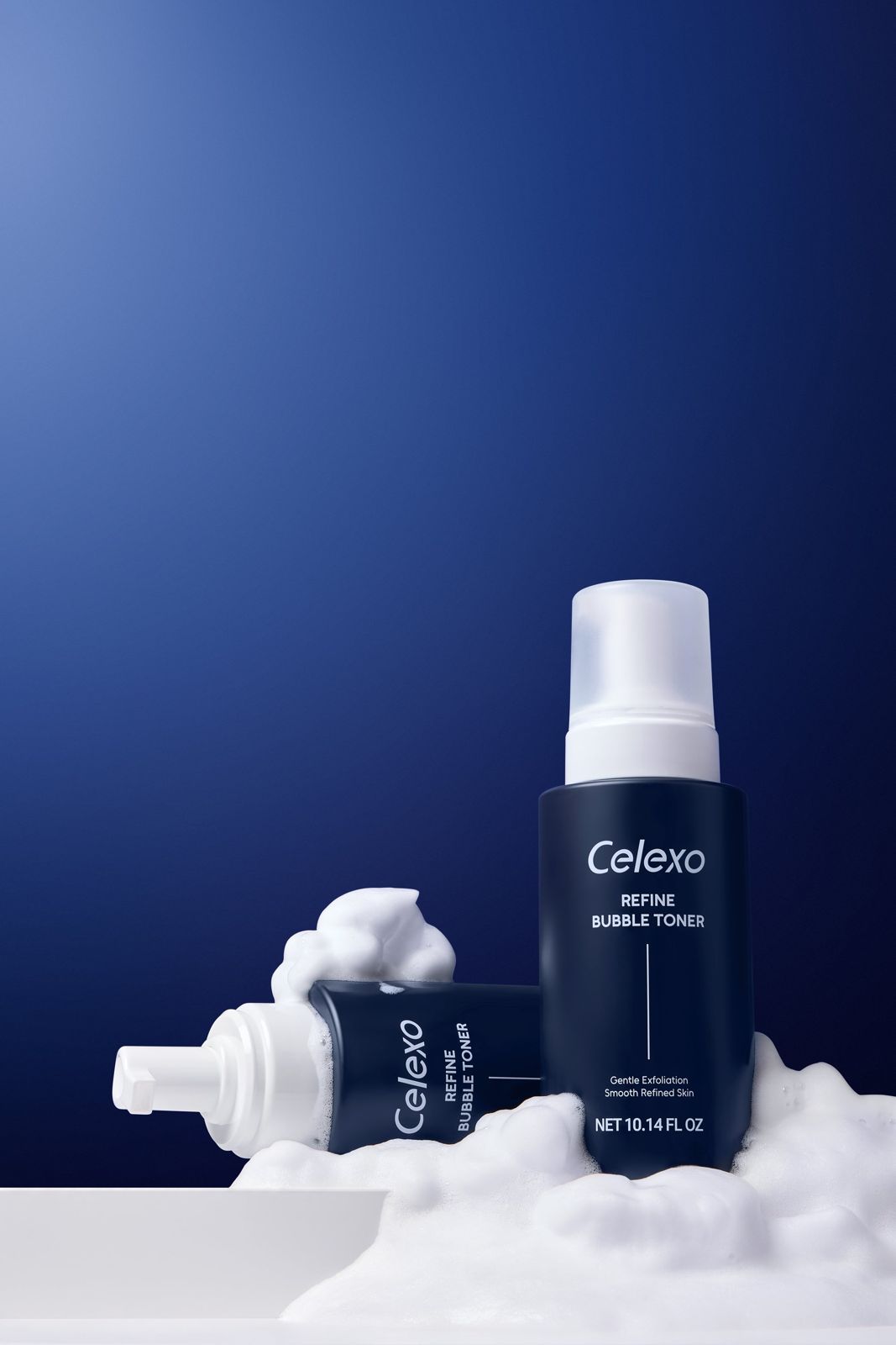 Celexo · 엑소테라피 스킨케어 — 토너 제품 2병을 거품과 함께 배치한 연출컷, 블루 배경