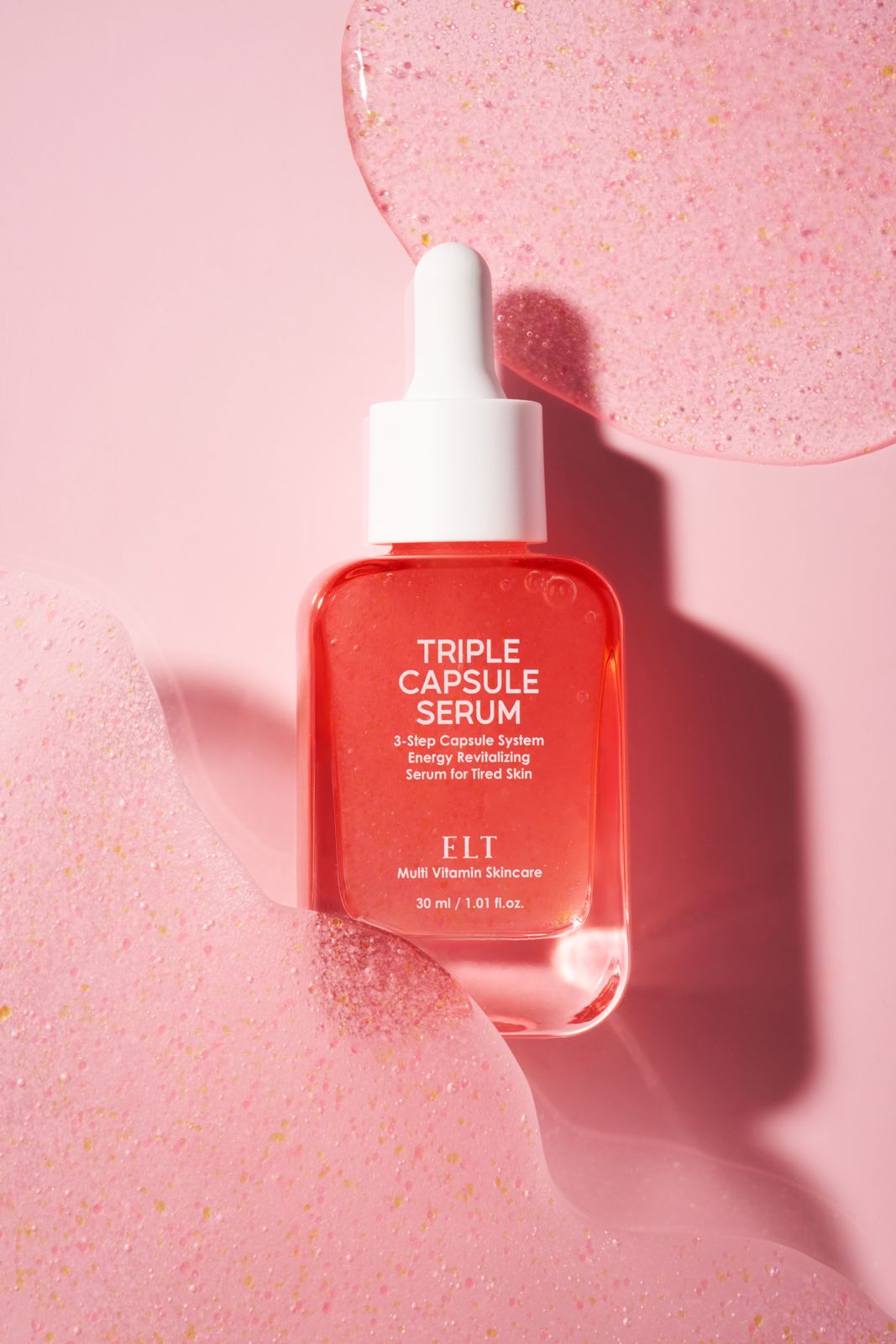 ELT COSMETIC · 캡슐세럼 — 탑뷰 구도, 제형이 넓게 퍼진 텍스처 배경 위 병 연출컷