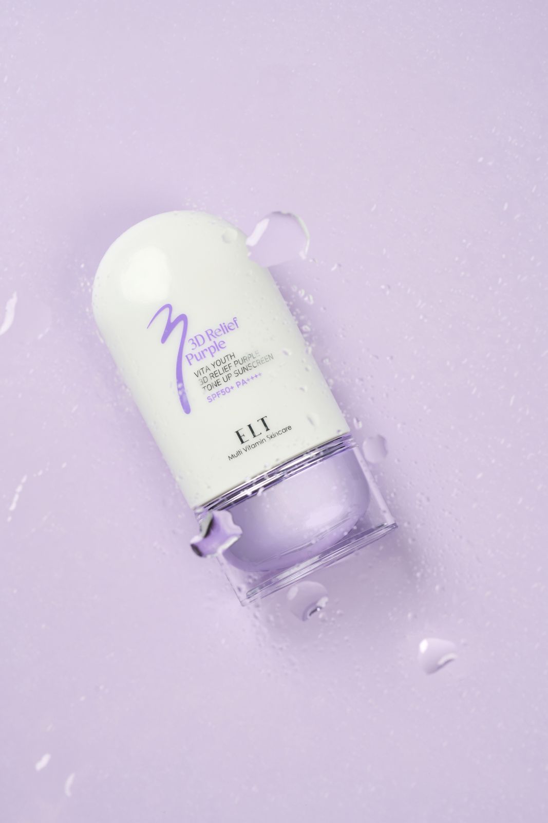 ELT COSMETIC · 선스크린 — 탑뷰 구도, 물방울이 흩뿌려진 표면 위 제품 연출컷