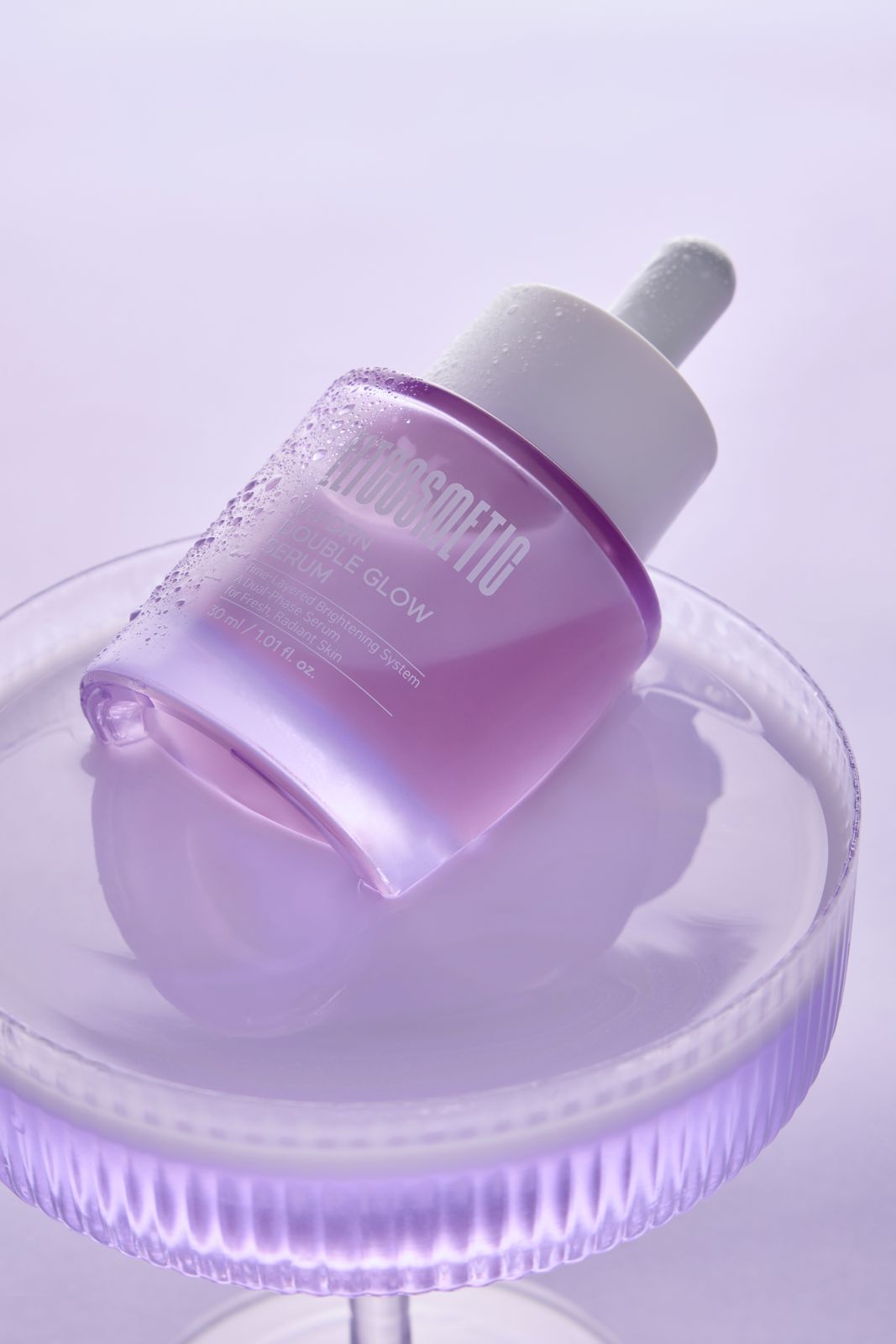 ELT COSMETIC · V-PDRN 세럼 — 유리 받침대 위 병을 눕혀 제형에 담근 연출컷