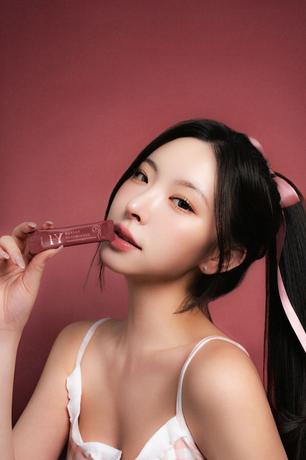 HANYAN · 건강기능식품 (모델컷) — 동일 파자마 세트, 사쉐를 입가에 대고 정면을 응시하는 클로즈업 모델컷