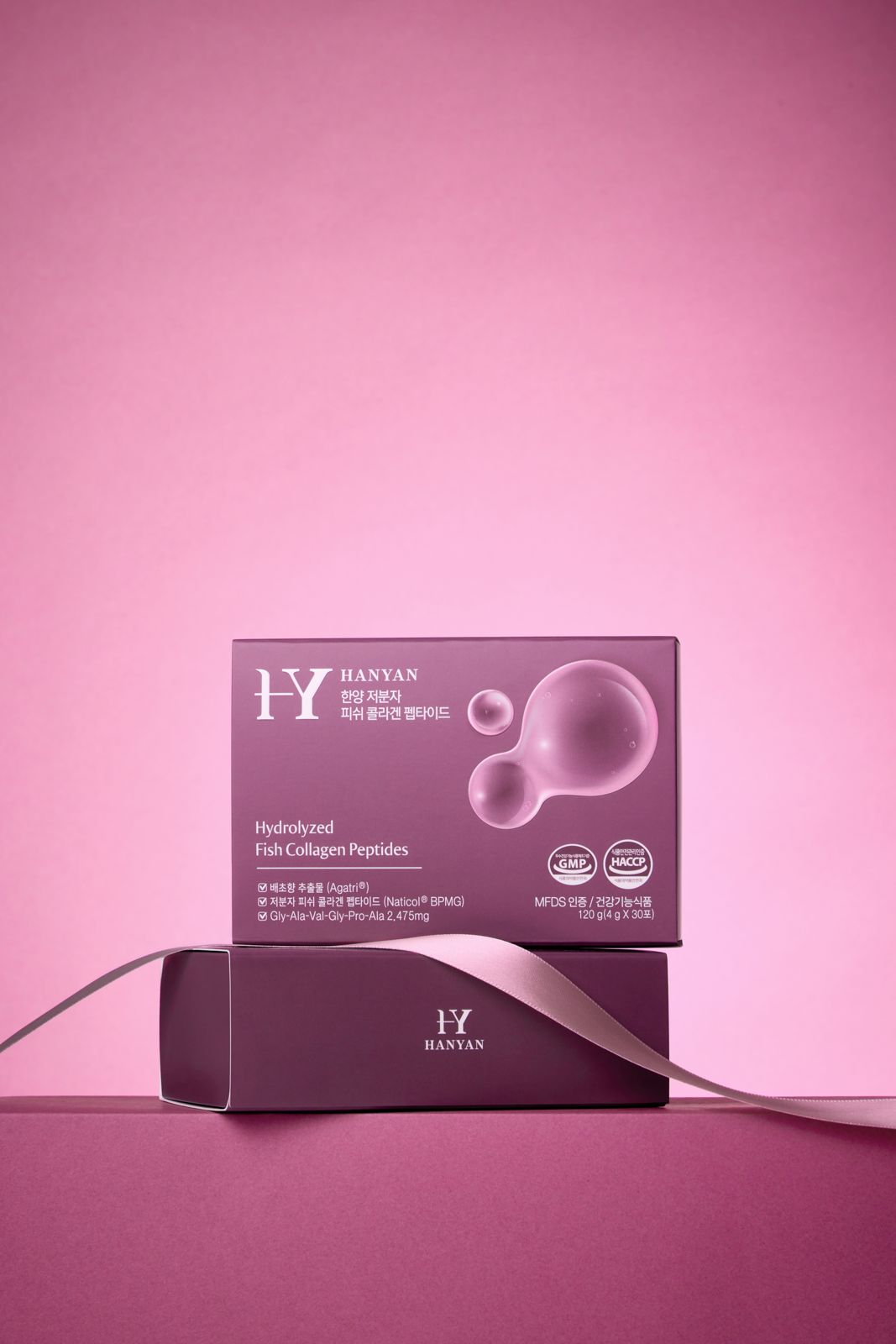 HANYAN · 건강기능식품 — 핑크 배경에 박스 2개를 쌓고 새틴 리본을 두른 럭셔리 연출컷
