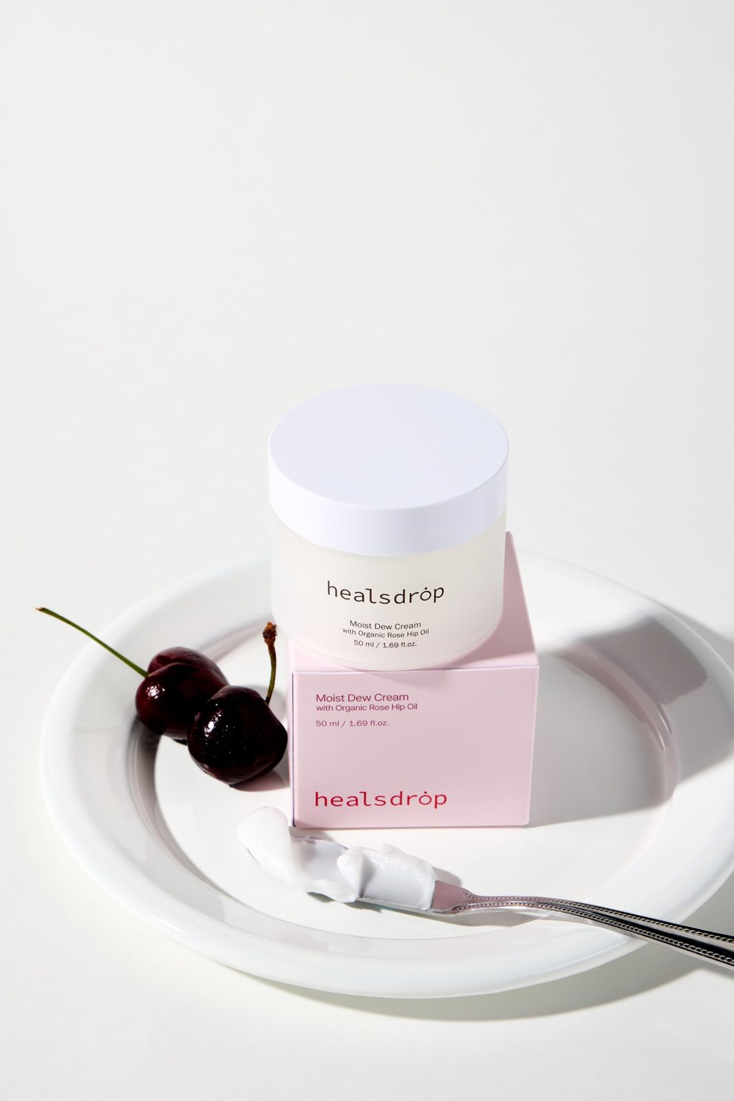 HEALSDROP · 크림 — 체리와 나이프에 덜어낸 크림 스와치를 접시에 함께 담은 연출컷, 화이트 배경
