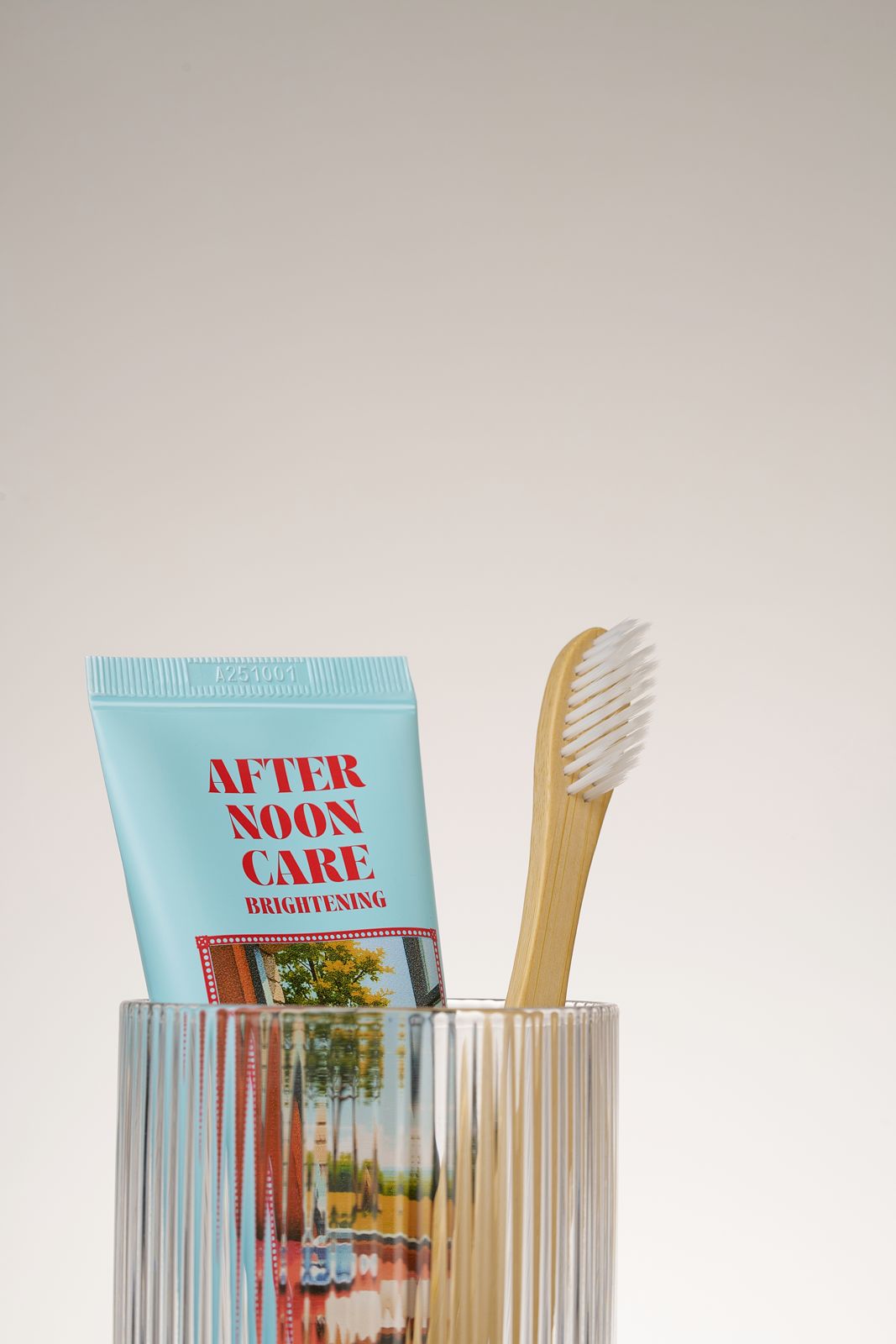 HEALTHY TEETH PLUS · 올데이케어 치약 — 애프터눈케어 치약과 나무 칫솔이 담긴 유리컵 클로즈업컷