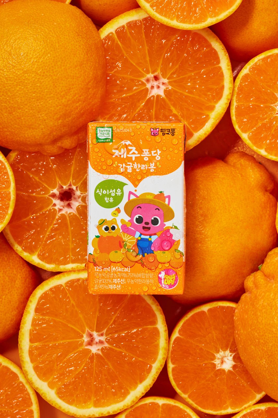 Jeju Pongdang · Tangerines Hallabong — 제주퐁당 감귤한라봉 제품을 신선한 감귤류 과일 사이에 배치한 컷