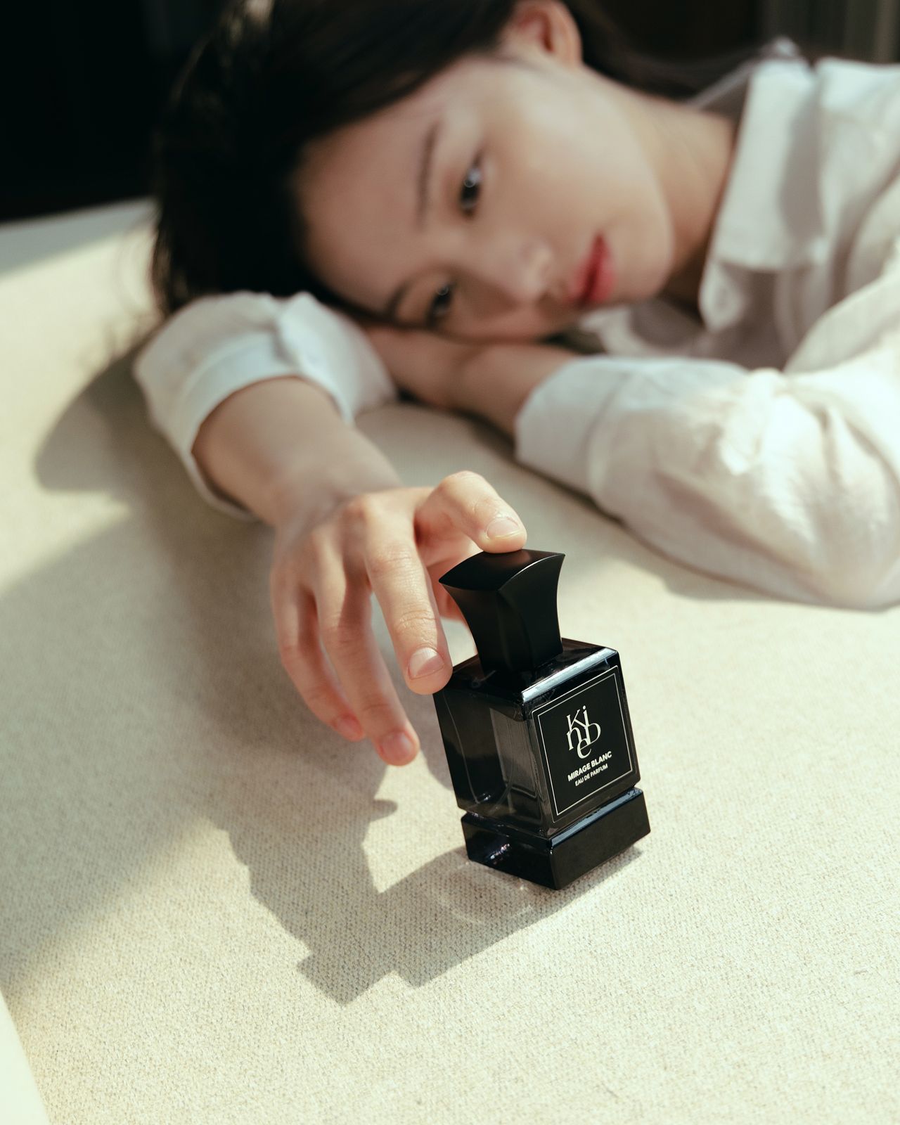 KINED · 모델촬영 — 탁자에 엎드려 향수병에 손을 뻗는 컷