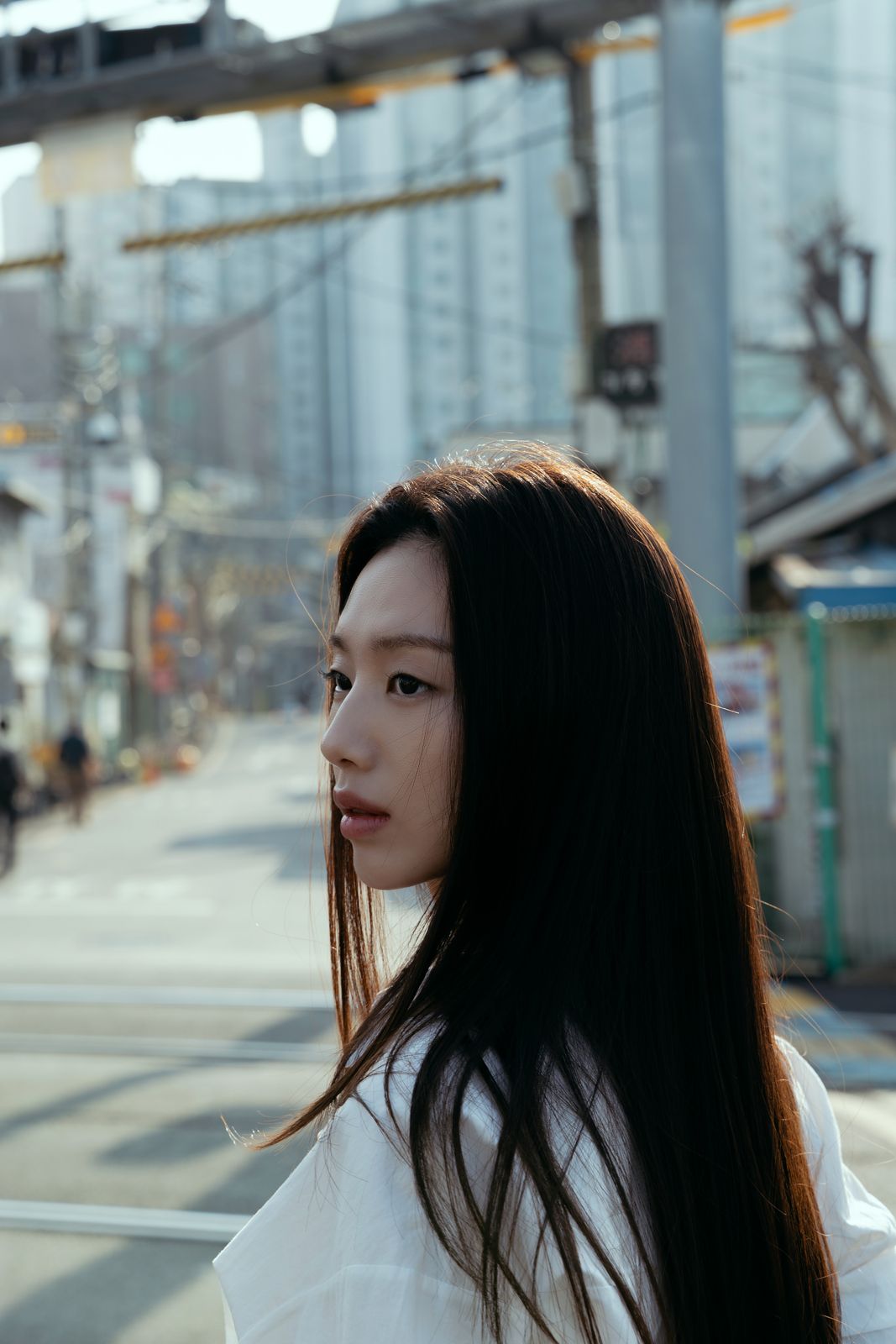 KINED · 모델촬영 — 도심 거리에서 옆모습으로 정면을 응시하는 컷(제품 미노출)