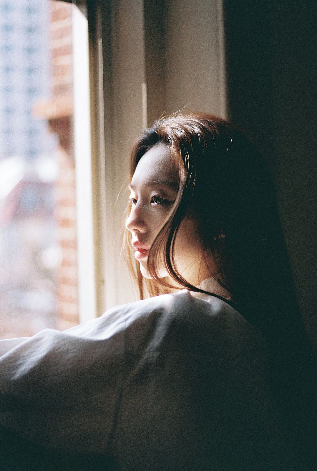 KINED · 모델촬영 — 창가에 기대어 밖을 바라보는 옆모습 필름톤 컷(제품 미노출)