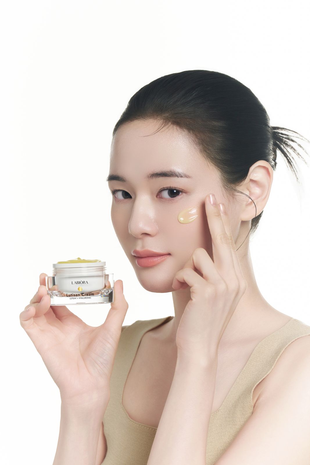 LABIORA · 세럼&크림 (모델컷) — 크림 용기를 들고 뺨에 바른 제형을 짚는 컷