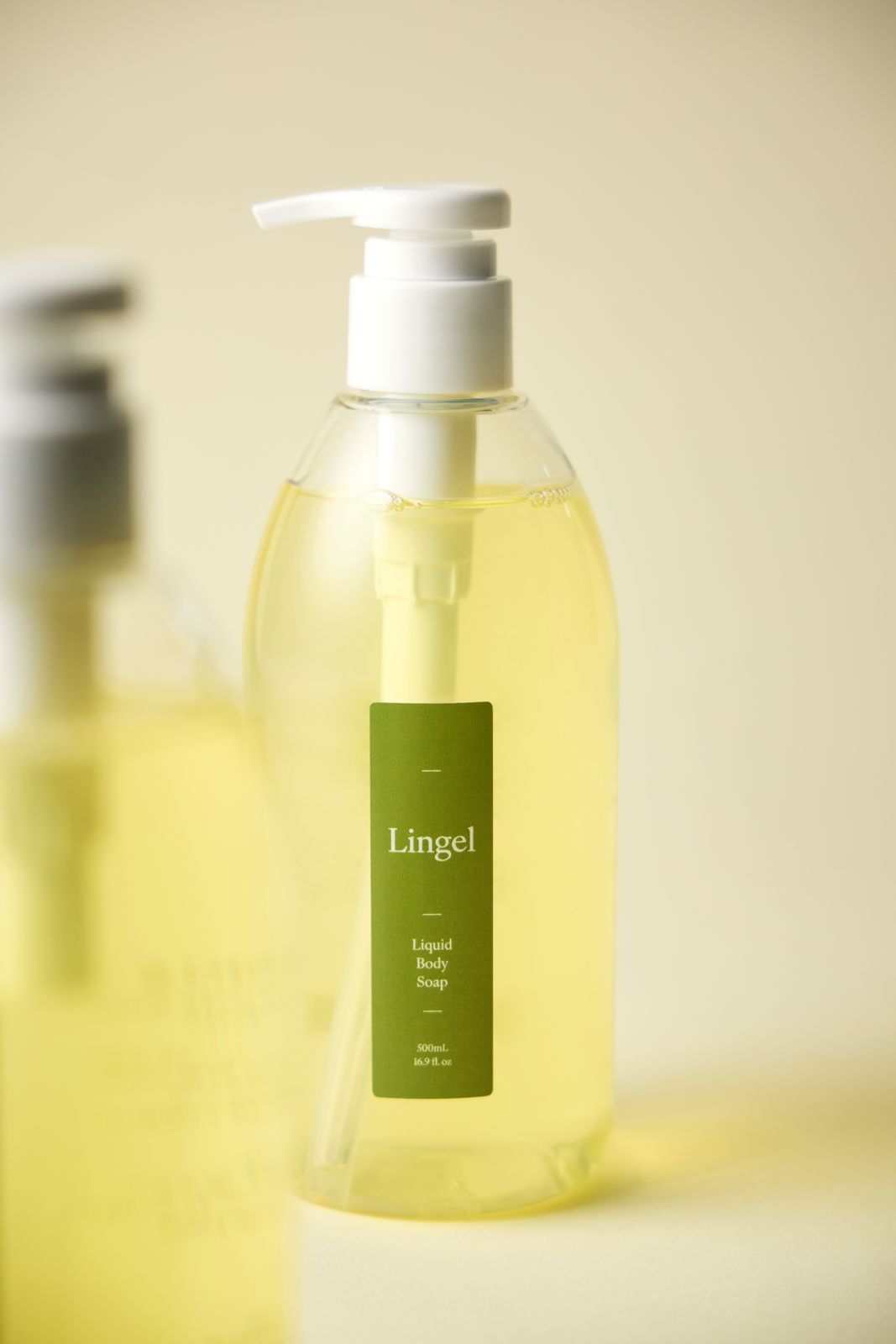 LINGEL · 리퀴드바디솝 — 정면 단독 펌프 용기컷, 배경에 아웃포커스된 다른 용기