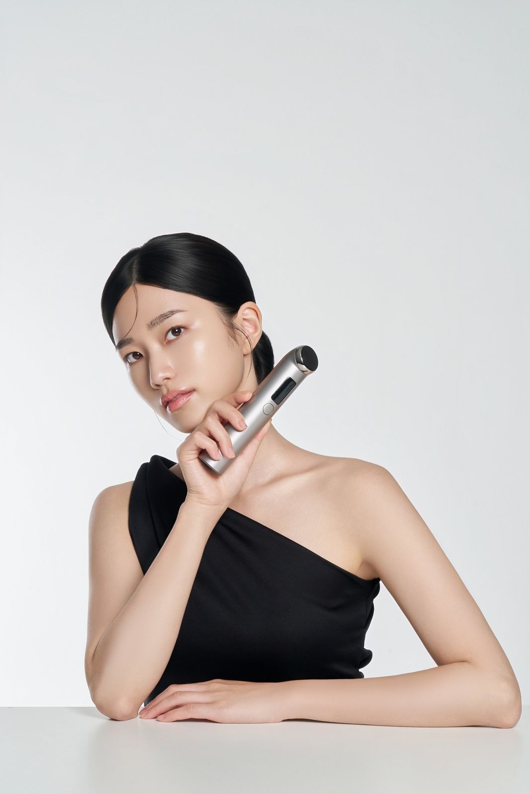 Lucelon · 디바이스 — 테이블에 팔을 얹고 턱 아래에 기기를 댄 모델 컷(메인 컷), 화이트 배경