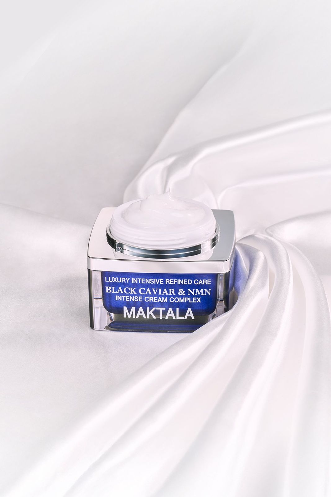 MAKTALA · 크림 — 블랙 캐비어 크림 오픈 컷, 화이트 새틴 패브릭 위에 연출