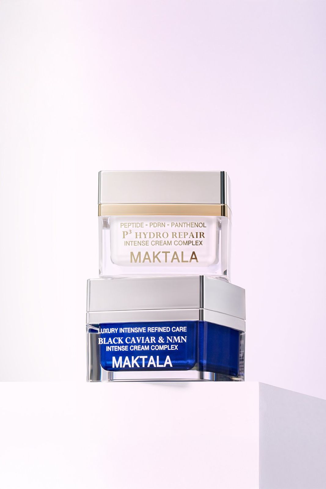 MAKTALA · 크림 — 두 제품을 쌓아 큐브 좌대 위에 올린 컷, 라벤더 배경