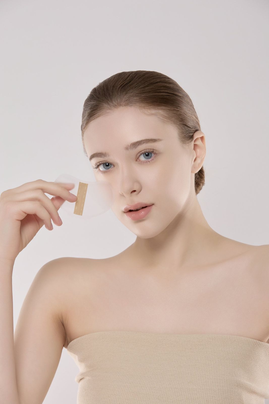 MUEZ · 선패치 — 모델이 패치를 손에 들고 얼굴 옆에 보여주는 컷, 화이트 배경