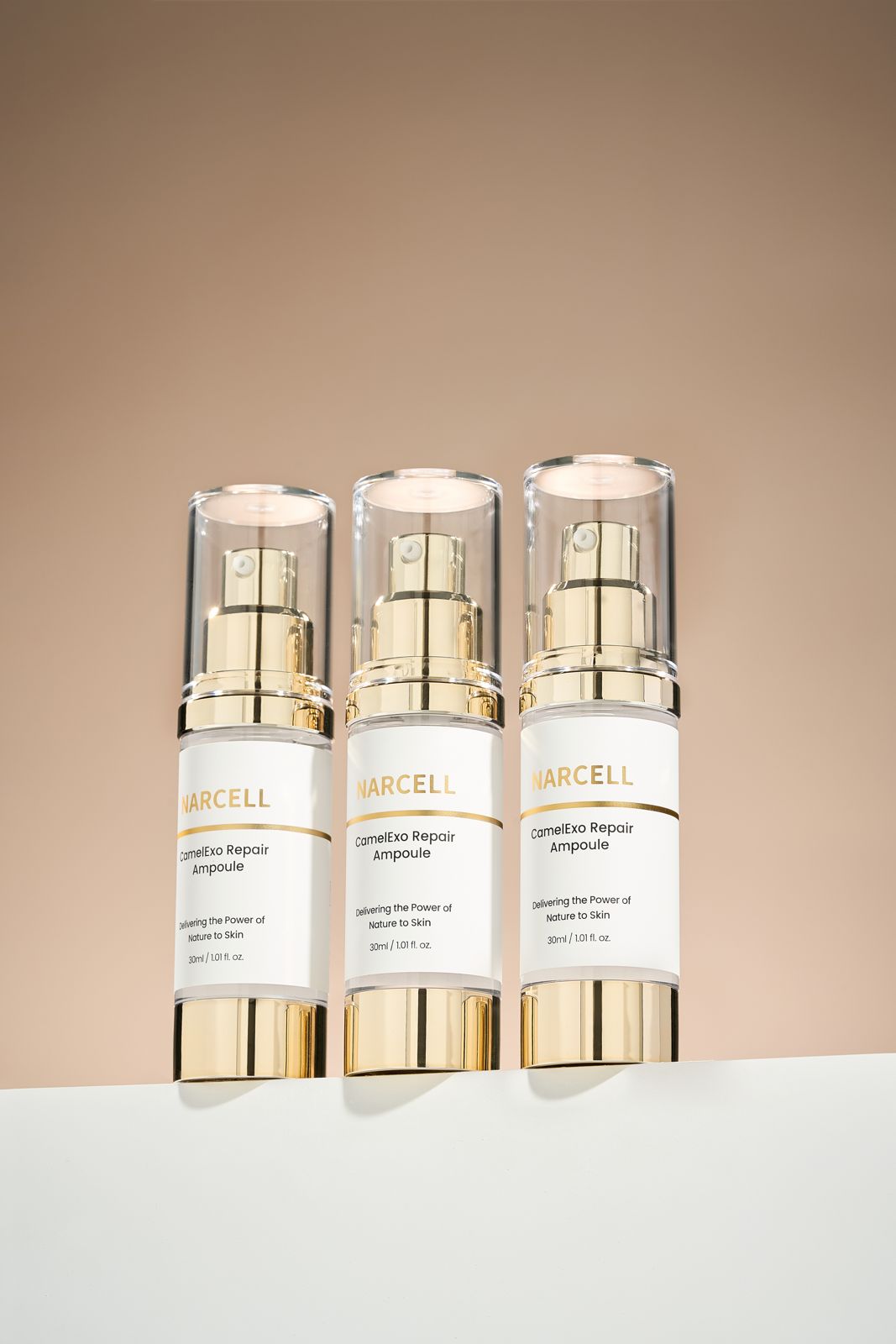 NARCELL · 앰플 — 화이트 좌대 위에 병 3개를 나란히 세운 그룹컷, 베이지 톤 배경