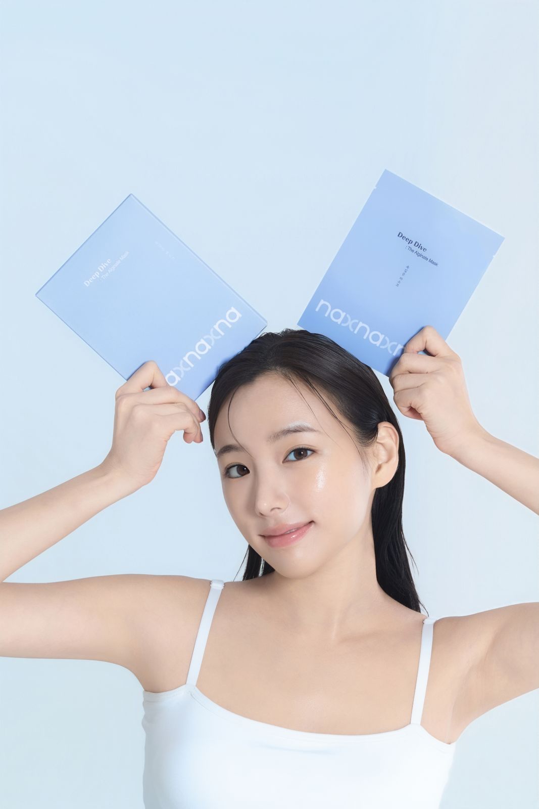 NAXNA · 모델촬영 — 마스크 파우치 두 개를 머리 위 양쪽에 든 발랄한 연출컷