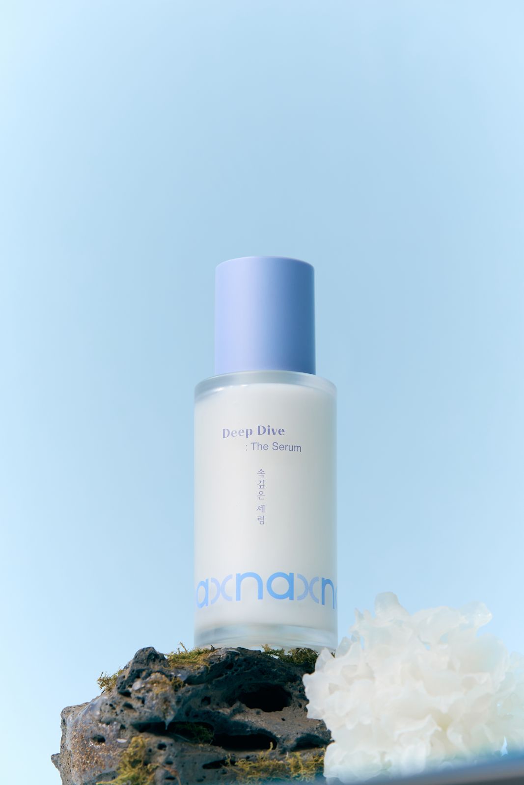 NAXNA · 제품촬영 — 이끼 낀 돌과 산호 소품 위에 제품을 올린 연출컷