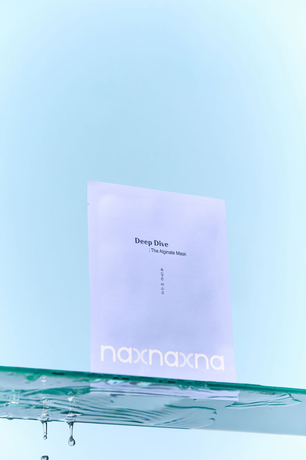 NAXNA · 제품촬영 — 물이 떨어지는 유리선반 위에 파우치를 올린 연출컷