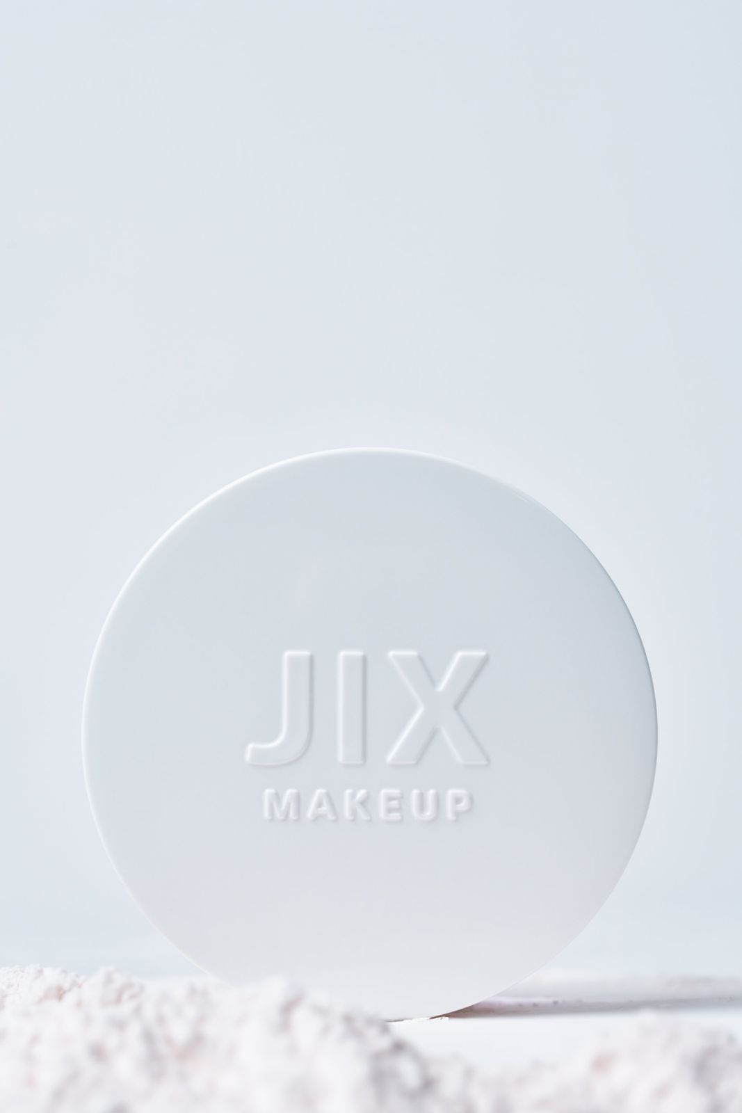 JIX · 파우더 — 제품 단독컷, 하단에 파우더가 살짝 흩날린 연출, 라이트블루 배경
