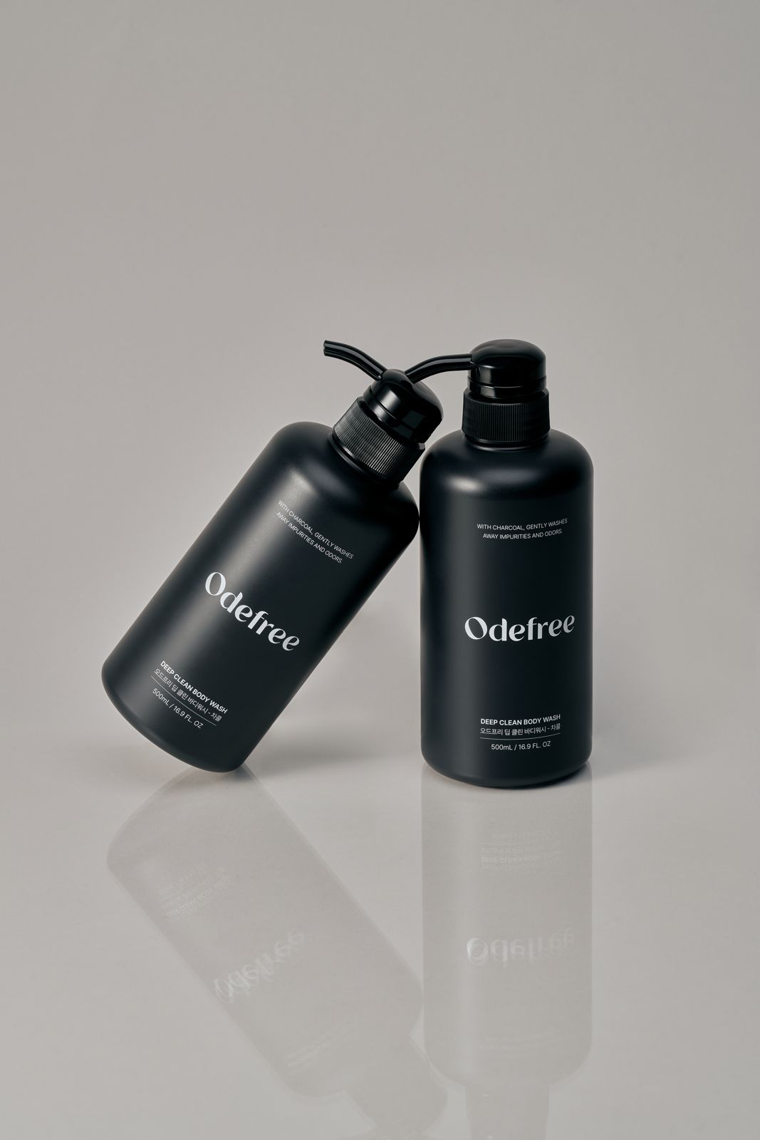ODEFREE · 바디워시 — 용기 하나를 기울여 다른 하나에 기댄 연출컷, 반사 바닥