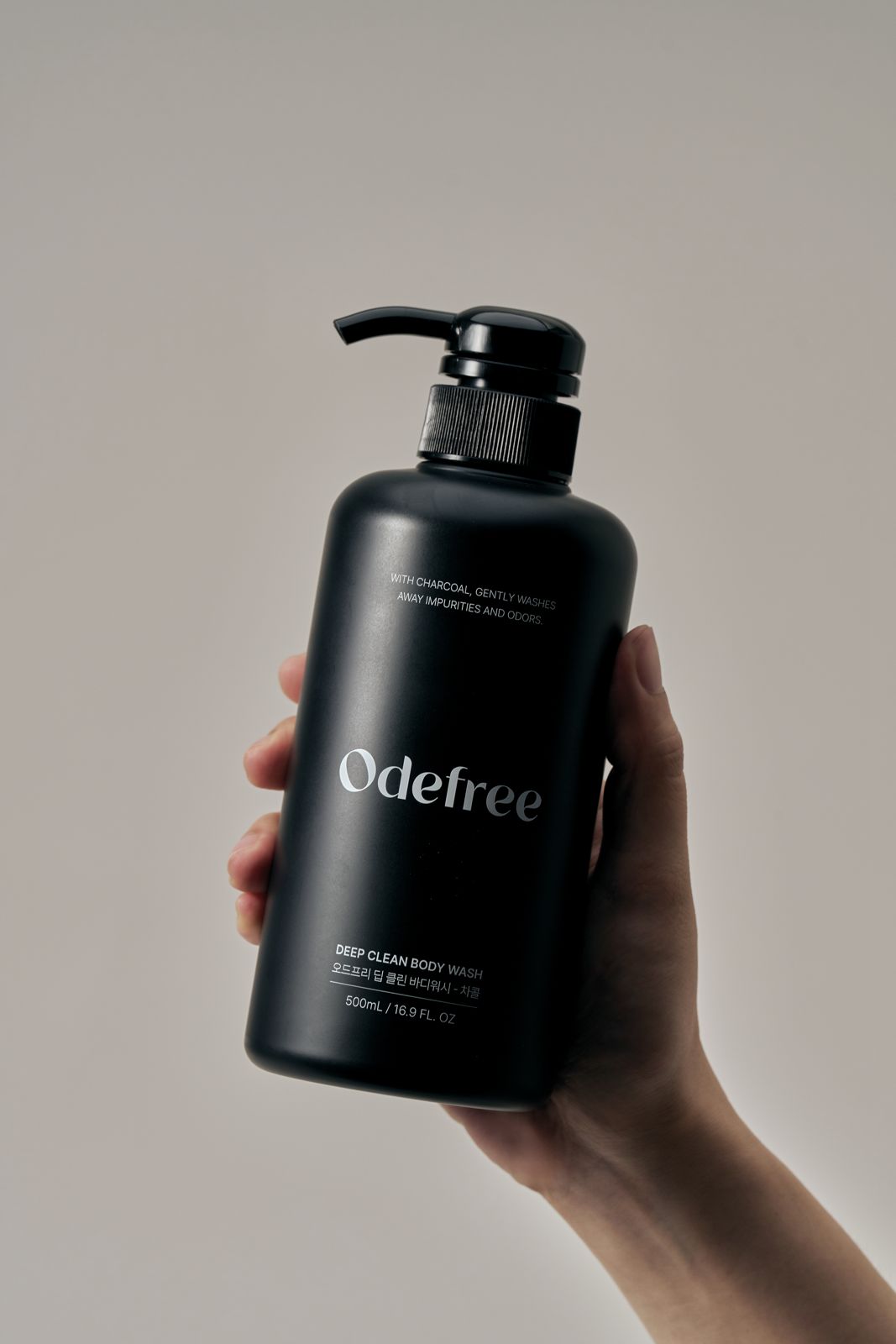 ODEFREE · 바디워시 — 손으로 용기를 들어올린 손모델컷, 웜톤 배경