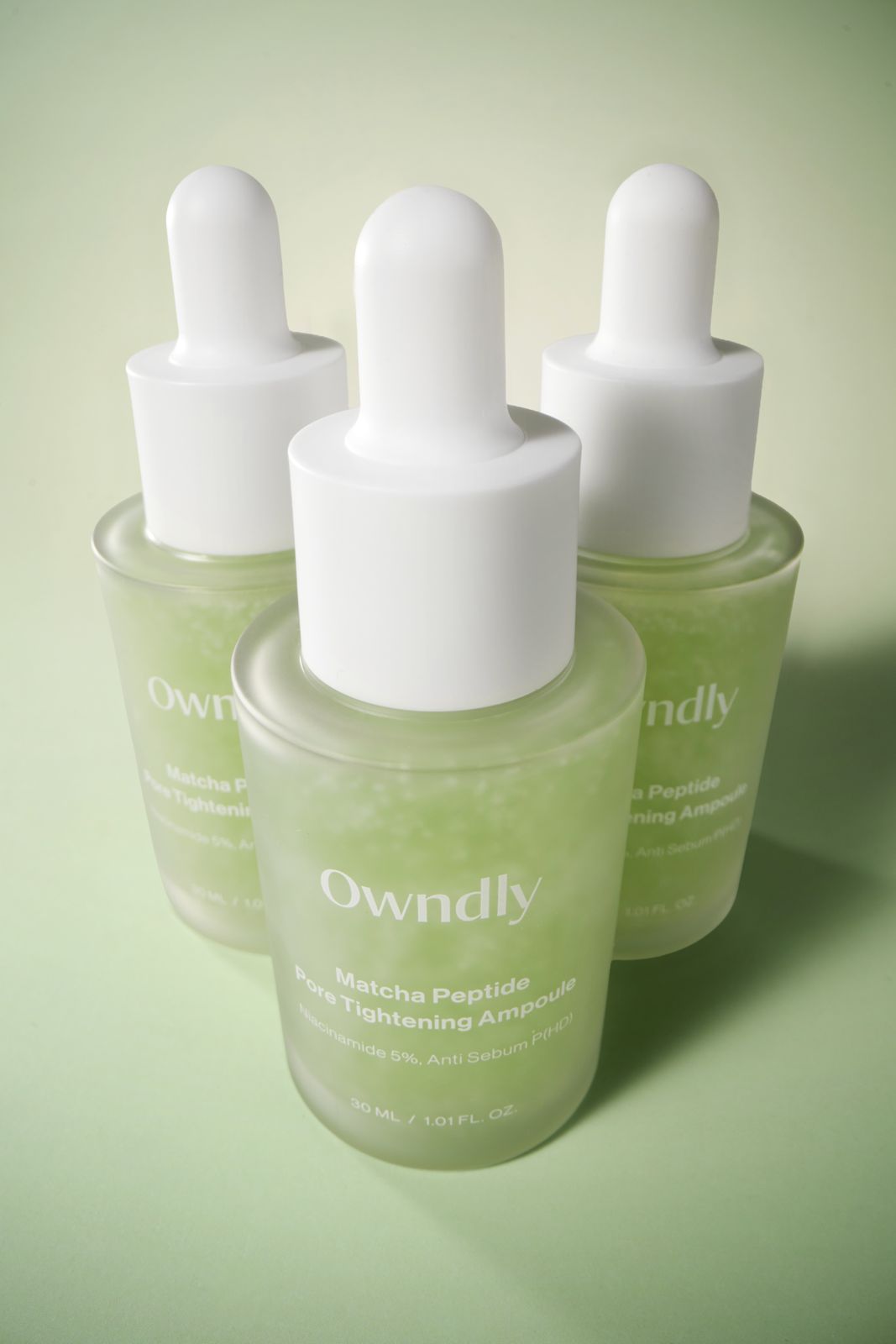 OWNDLY · 모공 타이트닝 앰플 — 병 3개를 삼각 구도로 배치한 그룹컷, 로우앵글