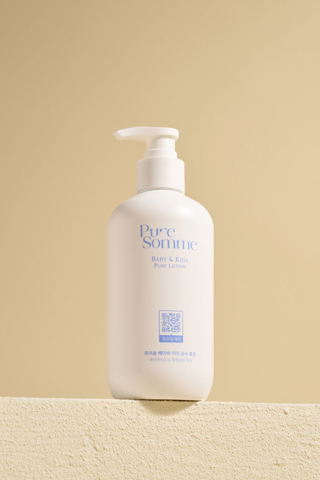 PURESOMME · 베이비로션 — 제품을 흰 받침 위에 세운 컷, 베이지 배경
