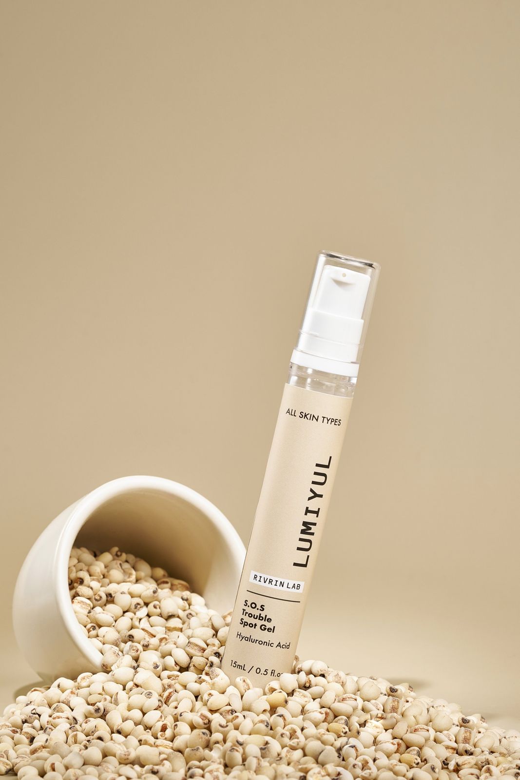 Rivrin Lab · 여드름패치겔 — 쏟아진 율무와 볼 옆에 제품을 세운 컷