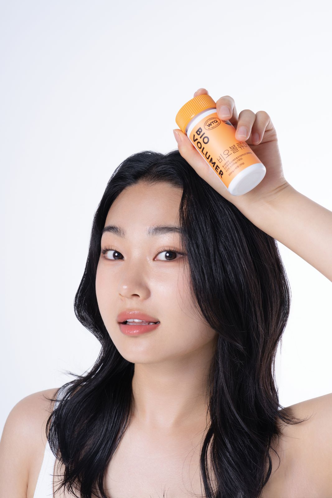 SH FOOD · 건강기능식품 (모델컷) — BIO VOLUMER 병을 머리 위에 얹고 정면을 보는 모델컷, 화이트 배경