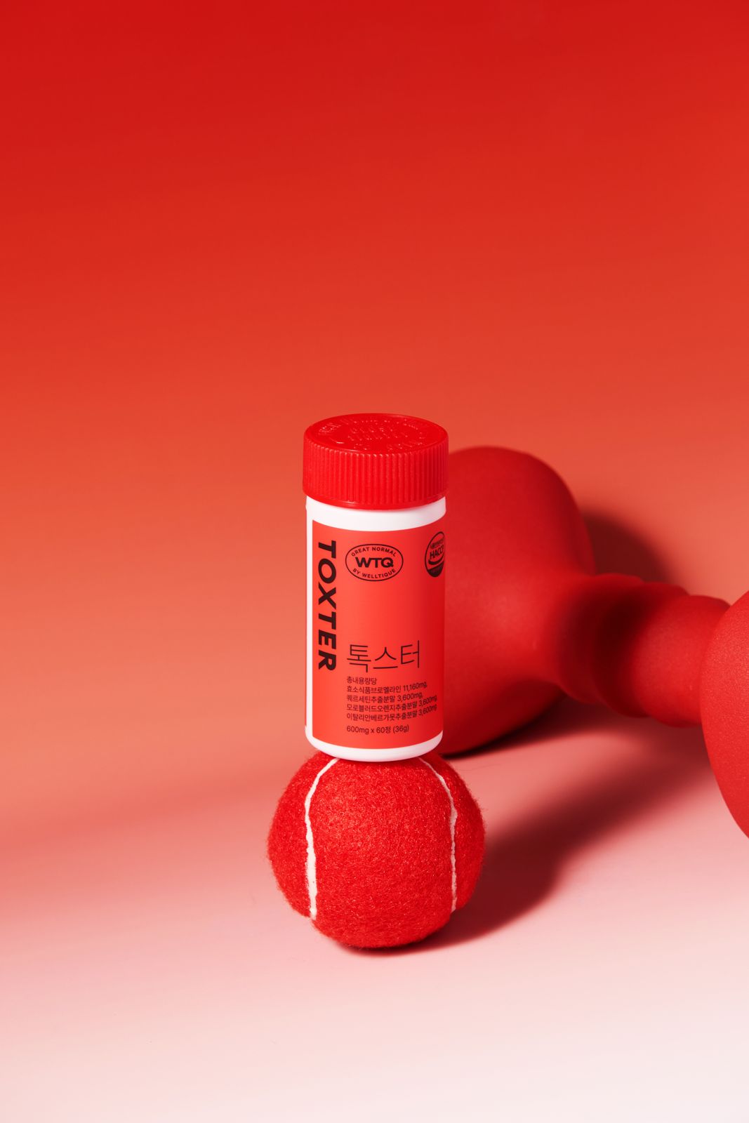 SH FOOD · 건강기능식품 — TOXTER 병을 테니스공 위에 세우고 덤벨을 배경에 배치한 컷