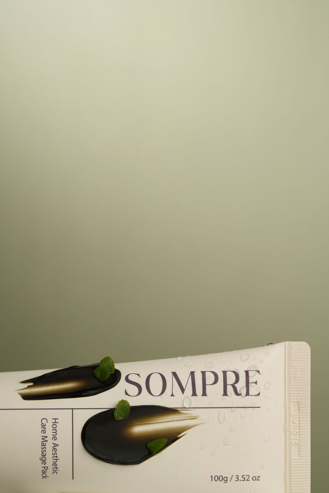 Sompre · 마사지팩 — 제형 스와치와 잎을 튜브 위에 얹은 클로즈업 컷
