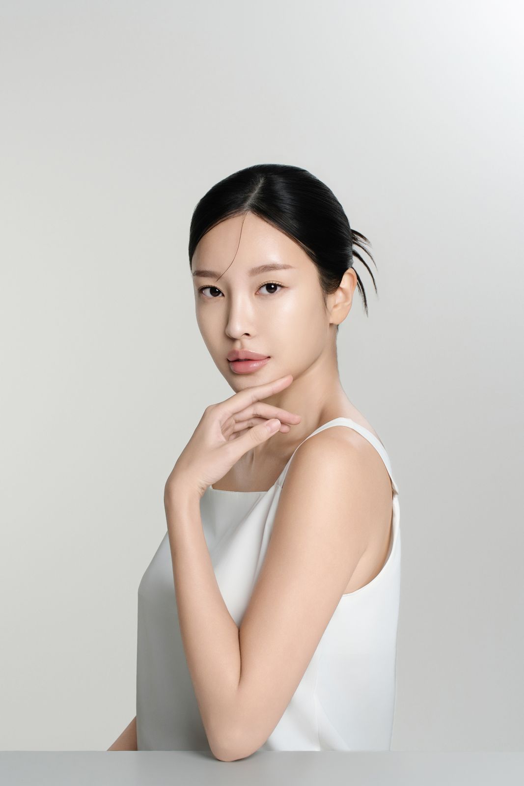 TRUHYAL100 · 모델촬영 — 화이트 캐미솔 착용, 손을 턱에 괴고 테이블에 앉은 상반신 모델컷