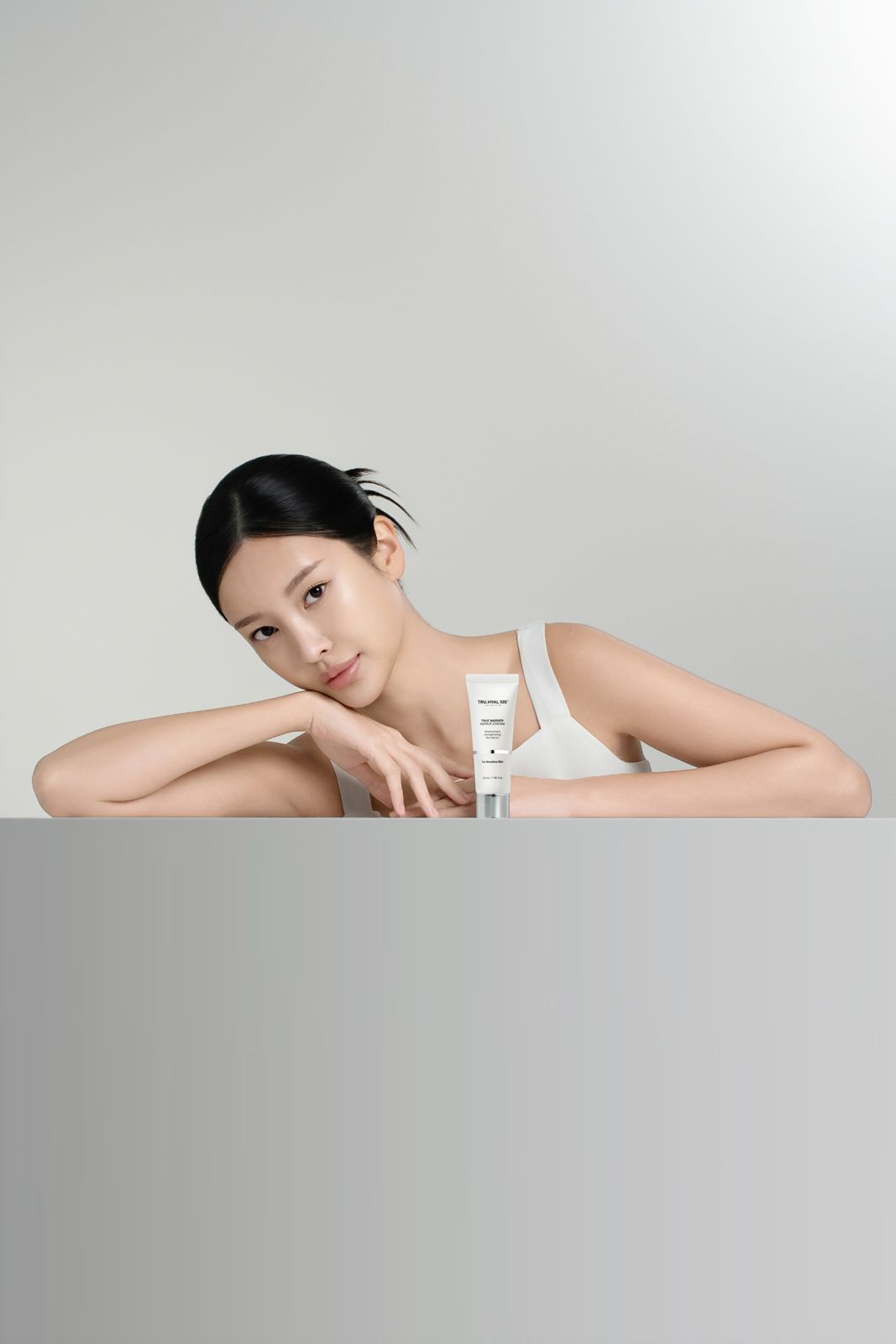 TRUHYAL100 · 모델촬영 — TRU.HYAL100 크림 튜브를 테이블에 올려두고 팔을 얹은 모델컷