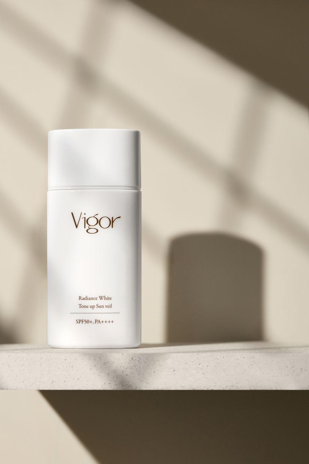 VIGOR · 선크림 — 돌 선반 위 단독 제품컷, 창문 그림자 연출