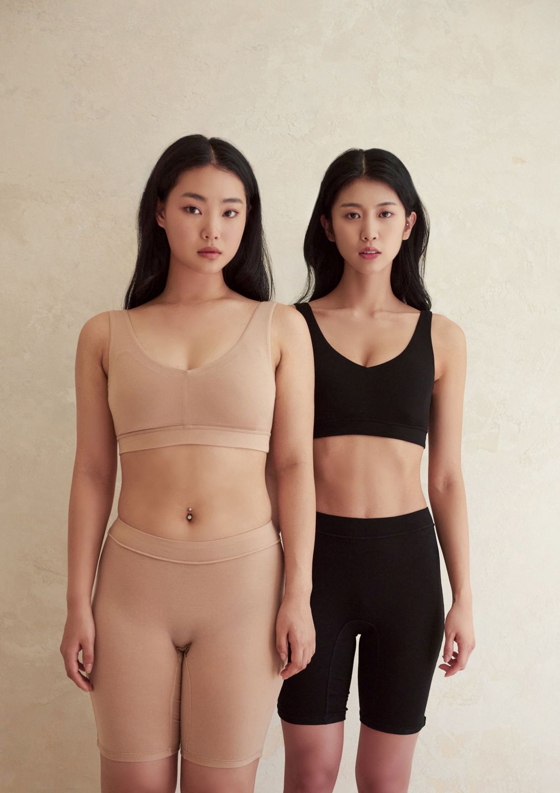 YEONHAN · 언더웨어 — 두 모델이 나란히 서서 누드톤과 블랙 두 가지 컬러의 이너웨어 세트를 비교해 보여주는 컷, 베이지 배경