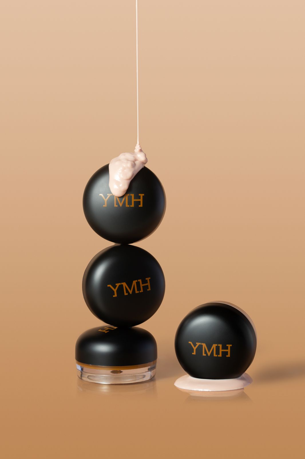 YMH · 컨실러 — 용기 2개를 쌓고 위에서 제형을 늘어뜨린 컷과 옆에 뚜껑 닫힌 용기를 함께 놓은 구성